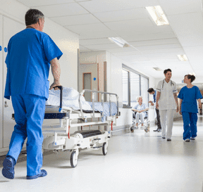 Zřízenec v nemocnici veze postel s pacientem na operaci