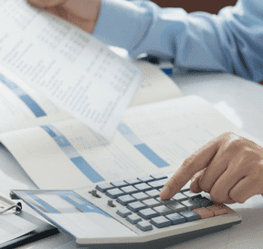 Člověk počítá na kalkulačce a dívá se do smluv